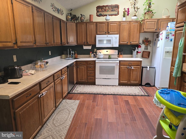 kitchen with light wood-type flooring, a textured ceiling, sink, lofted ceiling, and white appliances