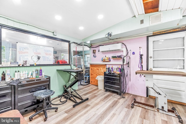 office area featuring vaulted ceiling with beams, light hardwood / wood-style floors, and a wall unit AC