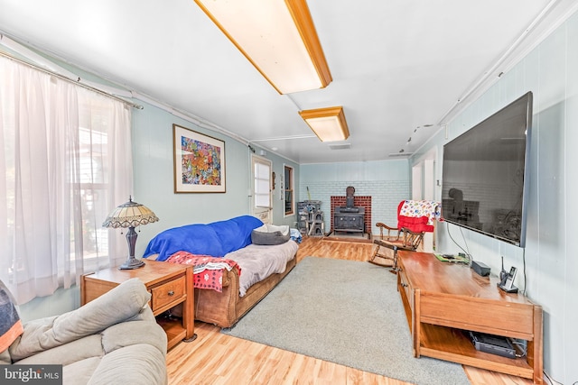 living room with ornamental molding, light hardwood / wood-style flooring, and a wood stove