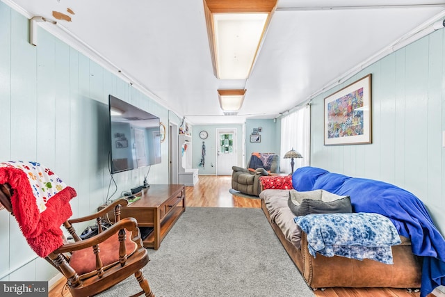 living room with wood-type flooring, wood walls, and crown molding