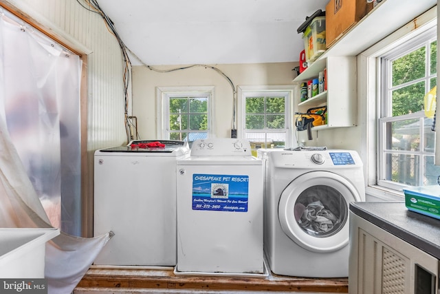 clothes washing area with washing machine and dryer and a wealth of natural light