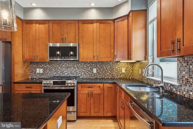 kitchen with dark stone counters, decorative backsplash, sink, and stainless steel appliances