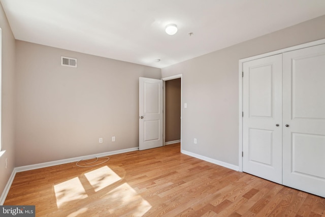 unfurnished bedroom with light wood-type flooring and a closet