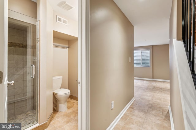 interior space featuring tile patterned floors, a shower with shower door, and toilet