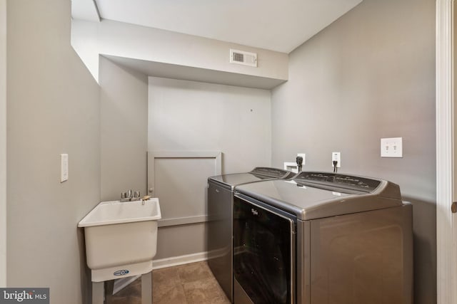 laundry area with separate washer and dryer and sink