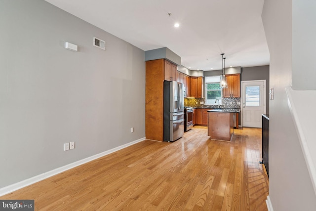 kitchen with tasteful backsplash, decorative light fixtures, stainless steel appliances, a center island, and light wood-type flooring