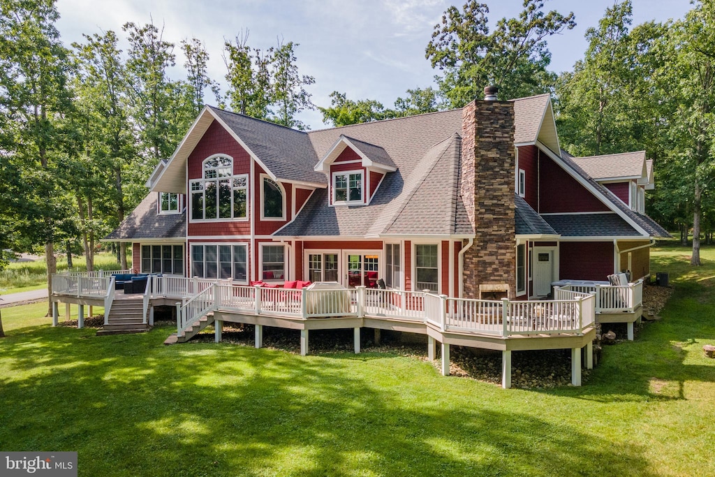 back of house with a deck and a lawn