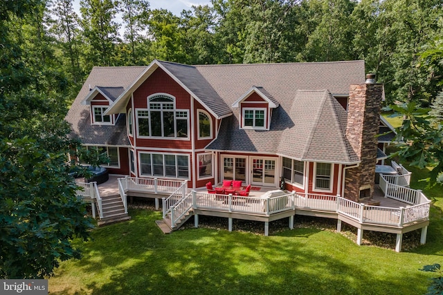 rear view of house featuring a wooden deck and a lawn