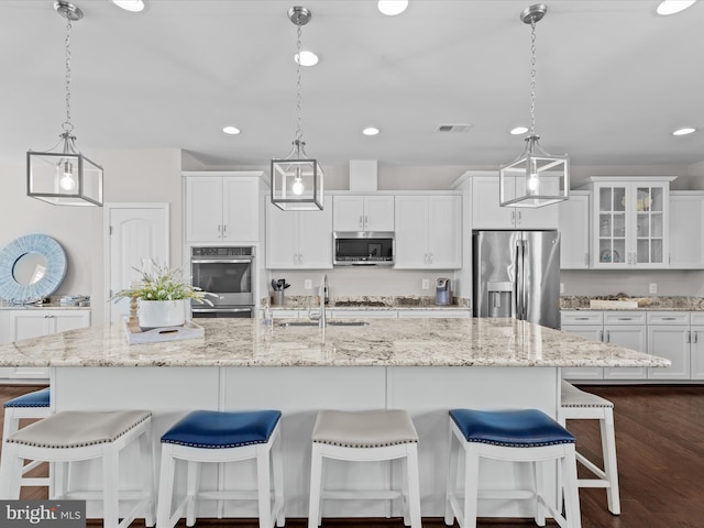 kitchen with a large island, stainless steel appliances, hanging light fixtures, and dark hardwood / wood-style flooring