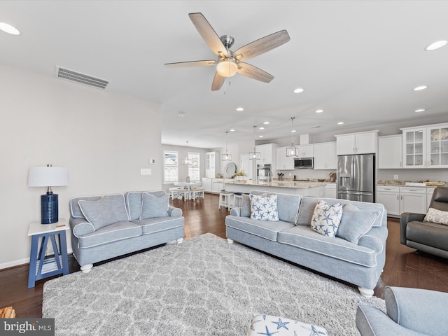 living room featuring ceiling fan and dark hardwood / wood-style flooring