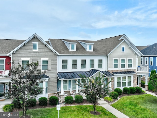 view of property featuring a balcony and a front lawn