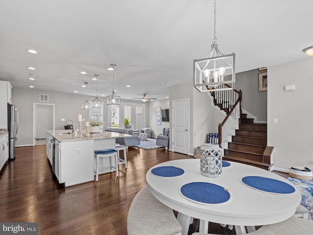 dining area featuring ceiling fan with notable chandelier, dark hardwood / wood-style flooring, and sink