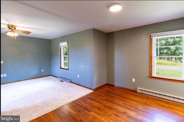 empty room featuring wood-type flooring, ceiling fan, and a baseboard radiator