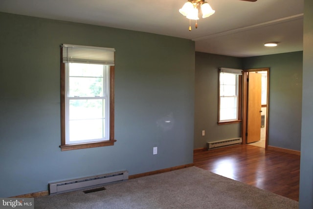 spare room with dark hardwood / wood-style flooring, a wealth of natural light, and a baseboard radiator