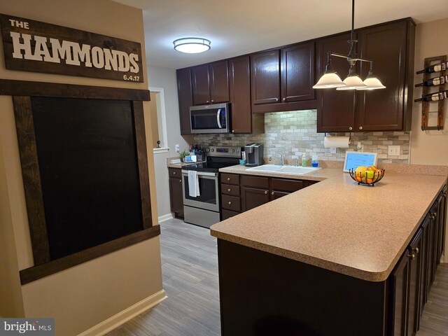 910 Sapphire Ct, Salisbury, MD 21804 - kitchen featuring appliances with stainless steel finishes, a sink, backsplash, light wood-style floors, and dark brown cabinets