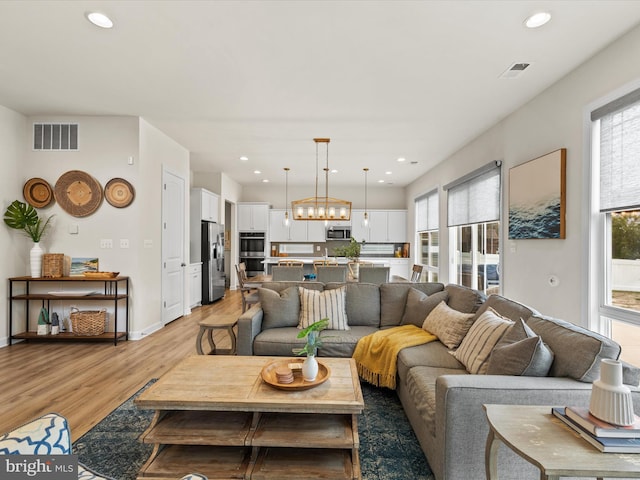 living room featuring light wood-type flooring and a chandelier