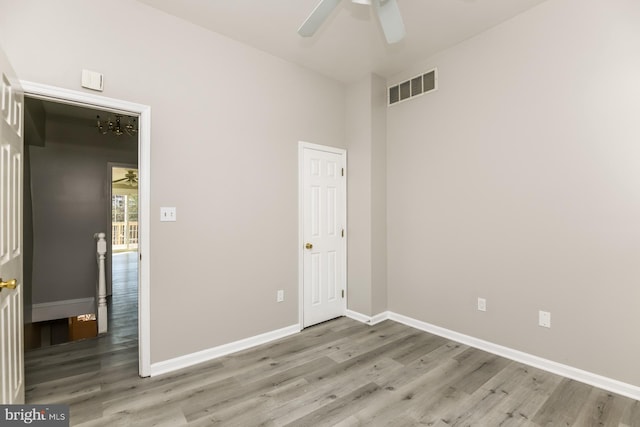 unfurnished bedroom featuring ceiling fan with notable chandelier and hardwood / wood-style floors