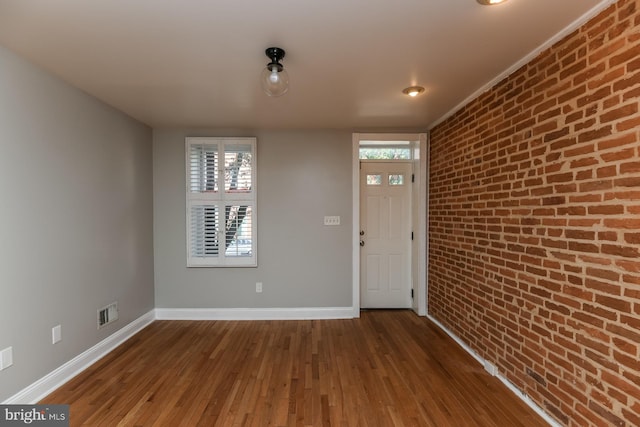 interior space featuring wood-type flooring and brick wall