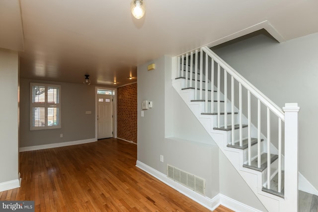 entrance foyer featuring wood-type flooring and brick wall