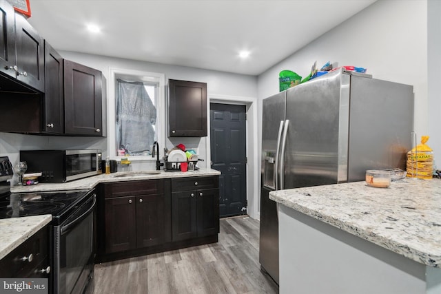 kitchen featuring light stone counters, sink, dark brown cabinets, light hardwood / wood-style flooring, and appliances with stainless steel finishes