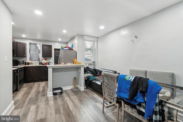 kitchen featuring dark brown cabinetry, cooling unit, appliances with stainless steel finishes, and light wood-type flooring