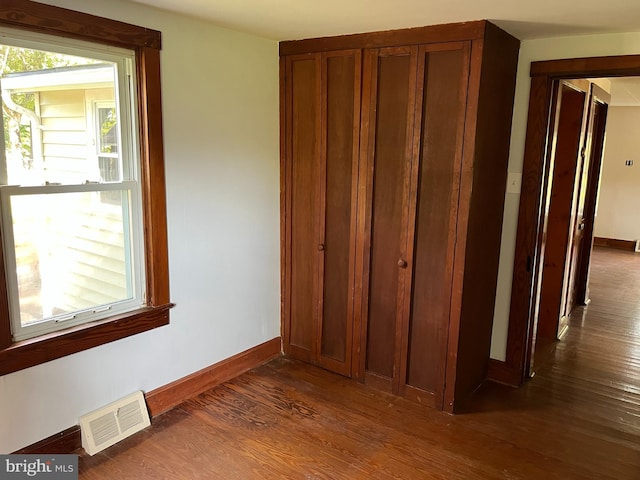 unfurnished bedroom with dark wood-type flooring and a closet