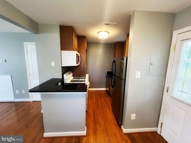 kitchen featuring appliances with stainless steel finishes, kitchen peninsula, electric panel, and dark hardwood / wood-style flooring