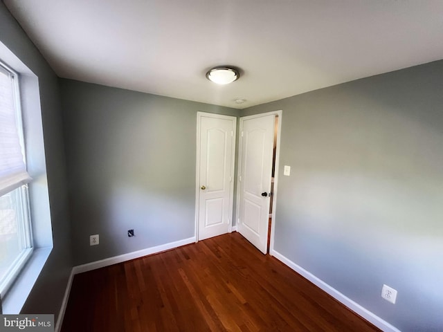 spare room with a wealth of natural light and dark hardwood / wood-style floors