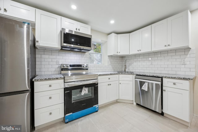 kitchen with light stone countertops, sink, white cabinets, and stainless steel appliances