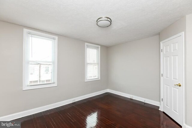 919 N Lakewood Ave, Baltimore, MD 21205 - unfurnished room with baseboards, a wealth of natural light, dark wood-type flooring, and a textured ceiling