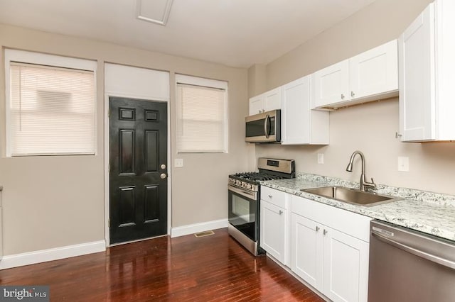919 N Lakewood Ave, Baltimore, MD 21205 - kitchen with white cabinetry, dark wood-style flooring, stainless steel appliances, baseboards, and a sink