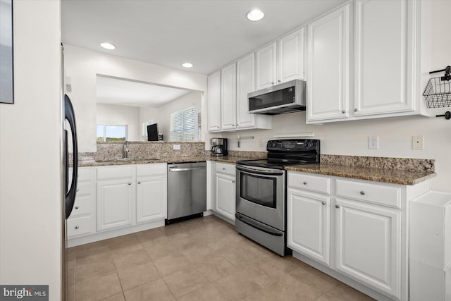 kitchen with appliances with stainless steel finishes, dark stone countertops, white cabinetry, and sink