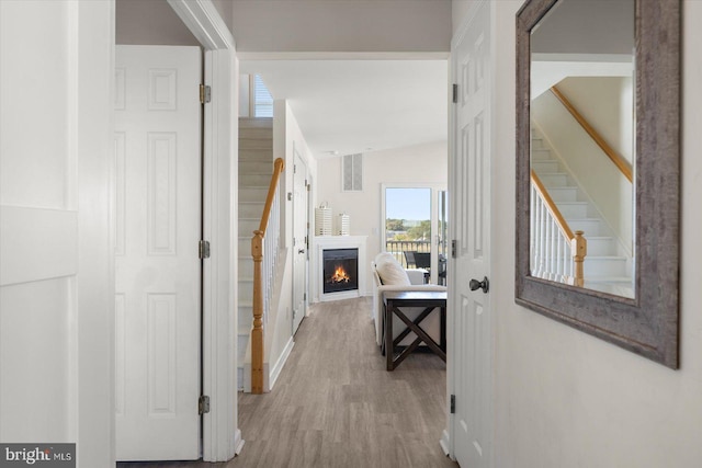 hall with light hardwood / wood-style floors and vaulted ceiling