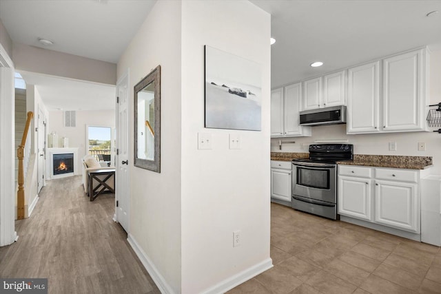 kitchen with stainless steel appliances, light hardwood / wood-style floors, and white cabinets