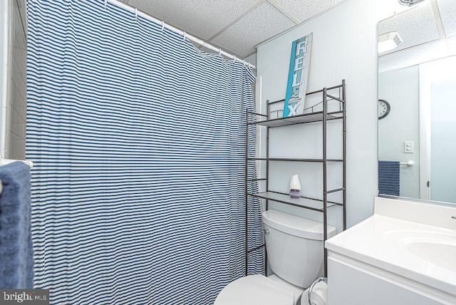 bathroom featuring curtained shower, a drop ceiling, vanity, and toilet