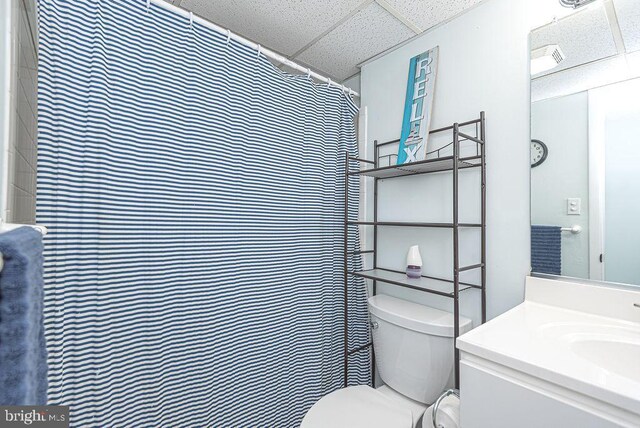 bathroom featuring a shower with shower curtain, toilet, a paneled ceiling, and vanity