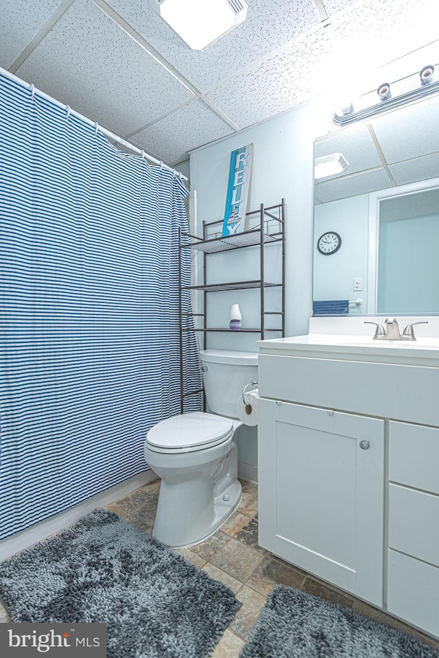 bathroom with vanity, a drop ceiling, toilet, and curtained shower