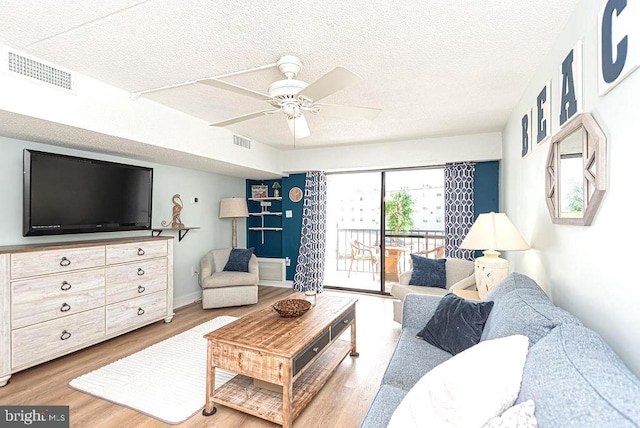 living room featuring ceiling fan, hardwood / wood-style flooring, and a textured ceiling