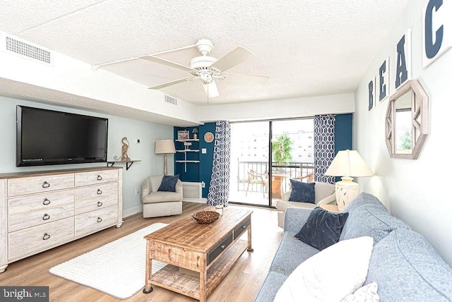 living area featuring visible vents, wood finished floors, ceiling fan, and a textured ceiling