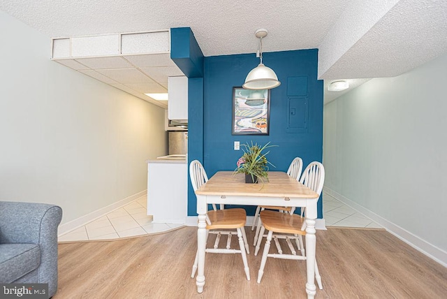 dining area with light hardwood / wood-style flooring and a textured ceiling