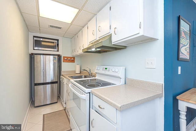 kitchen with light tile patterned floors, sink, white cabinetry, appliances with stainless steel finishes, and a drop ceiling