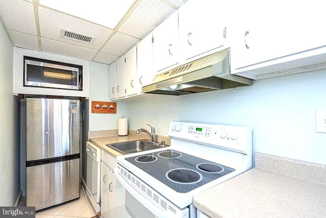 kitchen featuring white cabinets, light tile patterned floors, sink, stainless steel appliances, and a drop ceiling