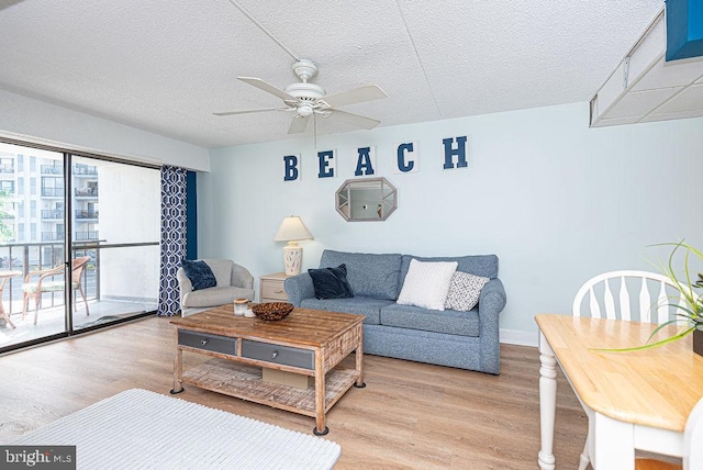 living room featuring light hardwood / wood-style floors, ceiling fan, and a textured ceiling