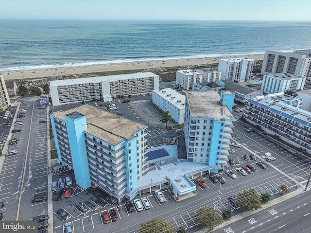 drone / aerial view featuring a water view, a view of the beach, and a city view