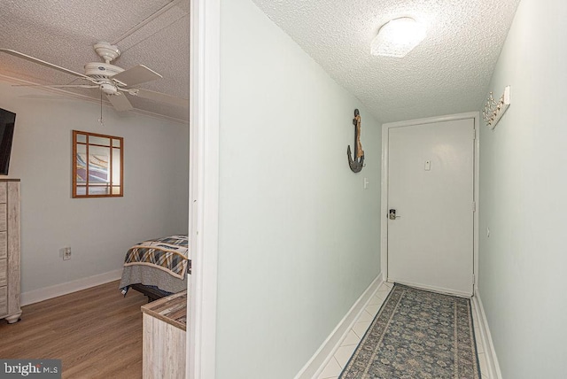 hall featuring baseboards, wood finished floors, and a textured ceiling
