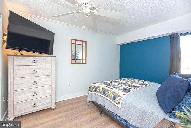 bedroom with crown molding, light wood-type flooring, baseboards, a textured ceiling, and ceiling fan