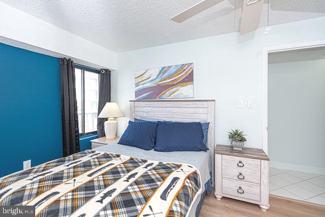 bedroom with a textured ceiling, ceiling fan, and hardwood / wood-style flooring