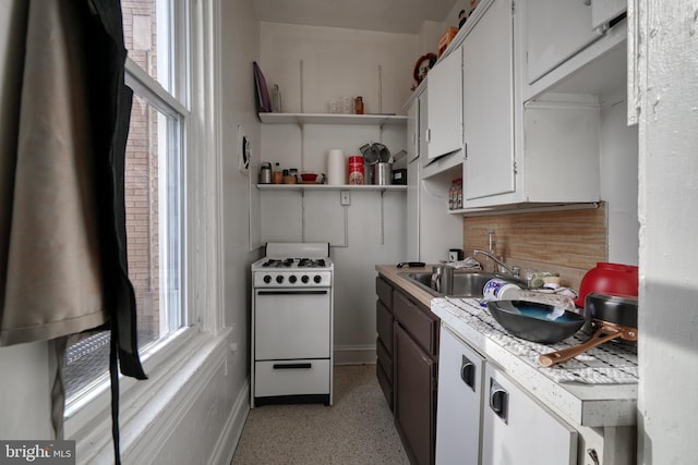 kitchen with white cabinetry, white gas range oven, and sink