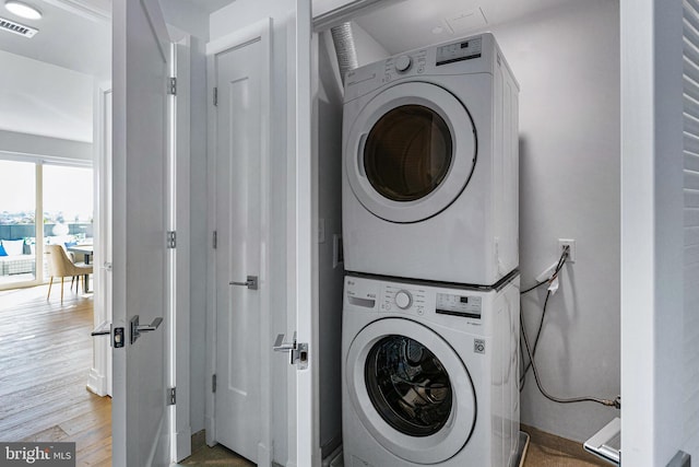 laundry room featuring stacked washer and clothes dryer and hardwood / wood-style floors