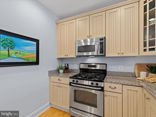 kitchen featuring light stone countertops, appliances with stainless steel finishes, and light hardwood / wood-style floors